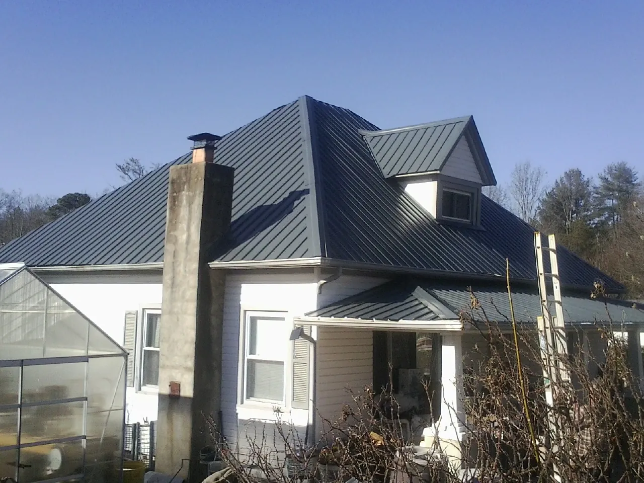 Dark blue standing seam metal roof on a white farmhouse with dormer — Slate & Tile Roof Repair by Roofing Brothers in Speedwell