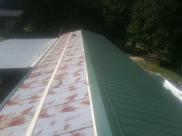 Old rusted panels beside newly installed green metal roofing — Wind Damage Roof Repair by Roofing Brothers in Speedwell