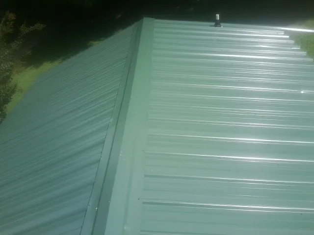 New green metal panels meeting at the ridge of a roof — Flat Roof Repair work by our crew in Speedwell