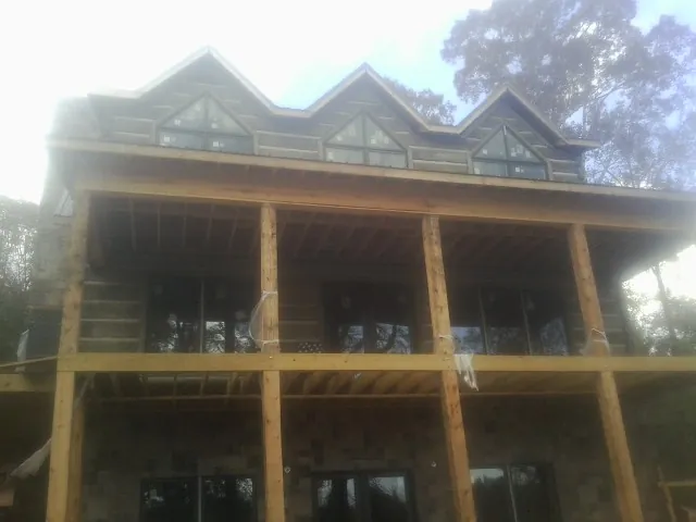 Dormers and porch framing on a large log home under construction — Roof Coating work by our crew in Speedwell