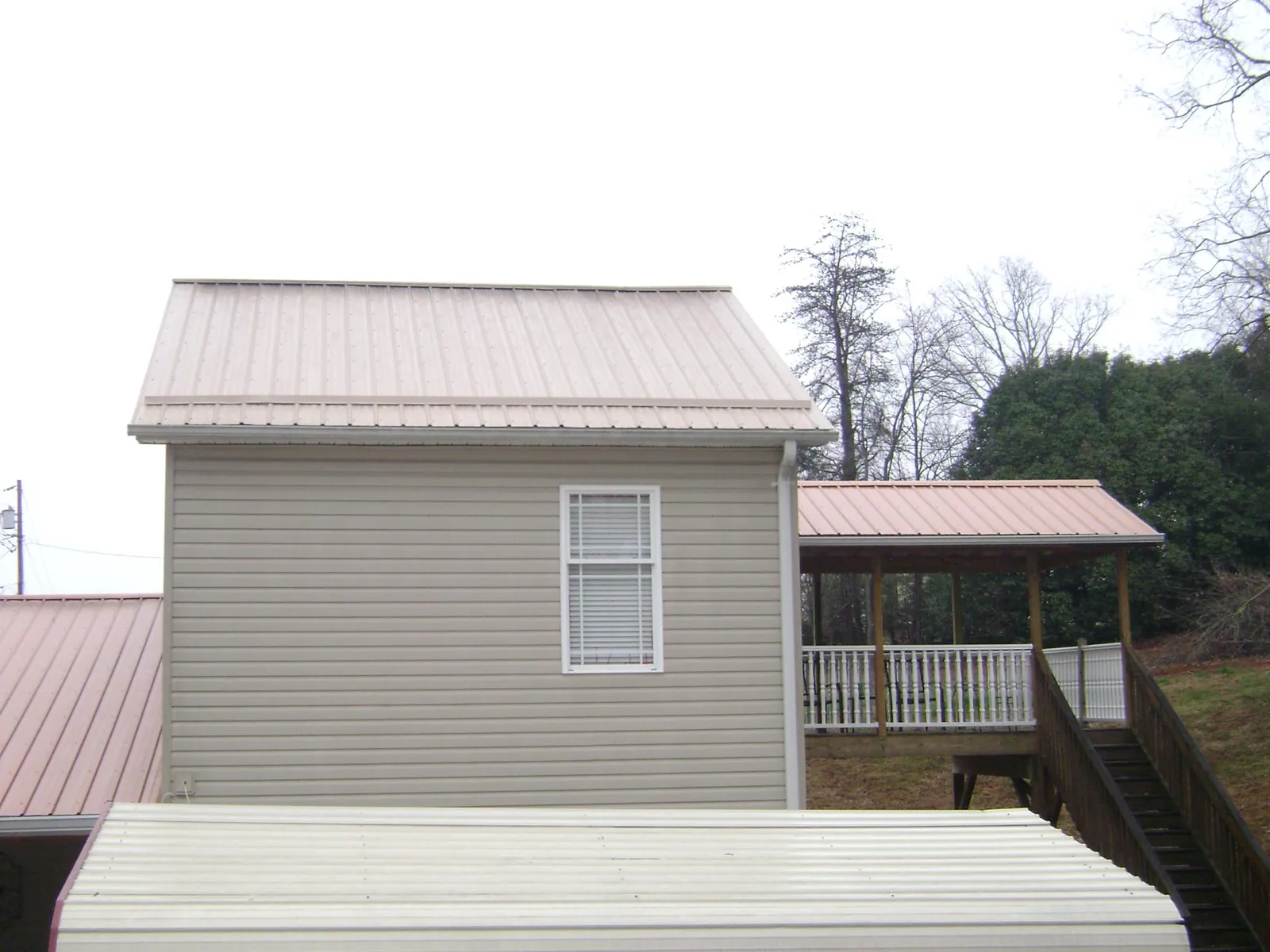 Tan metal roofs on a two story addition and attached porch, from a Roof Replacement job in Speedwell